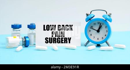 Medicina e concetto di salute. Una sveglia, pillole, iniezioni e una scheda con l'iscrizione - Low Back Pain Surgery Foto Stock