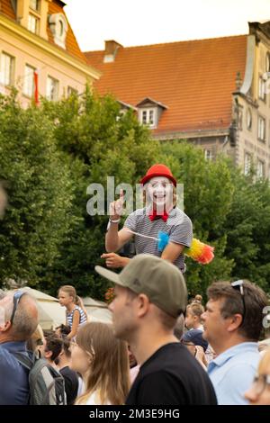 Gdansk, Polonia - 9 agosto 2022 Ritratto di clown fresco in parrucca luminosa. Parata durante la Fiera di Dominic a Danzica. Festival di intrattenimento in strada palafitte camminatore uomo in rosso giocoleria sorridente. Spettacolo teatrale per bambini al Foto Stock