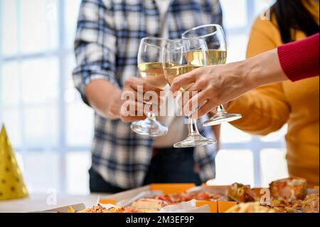 Immagine ravvicinata, gruppo di amici diversity che brindano e aggraffano i bicchieri di vino insieme durante la festa. Foto Stock
