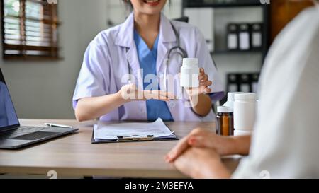 Una dottoressa asiatica professionista che spiega e fornisce istruzioni mediche alla paziente. immagine ritagliata Foto Stock