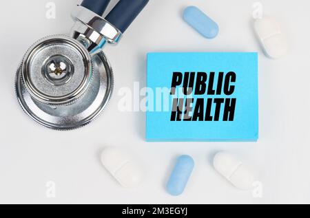 Medicina e concetto di salute. Su una superficie bianca si trovano pillole, uno stetoscopio e adesivi con l'iscrizione - la salute pubblica Foto Stock