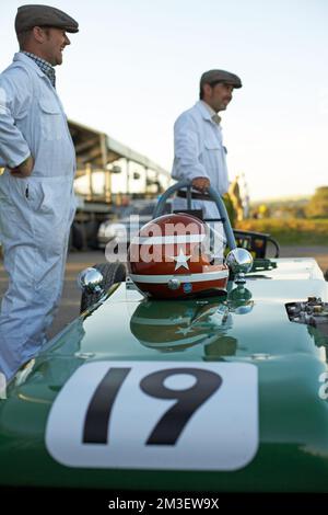 GOODWOOD, WEST SUSSEX/UK - Meccanica con tute bianche in fronte di auto da corsa d'epoca a Goodwood Revival . Foto Stock