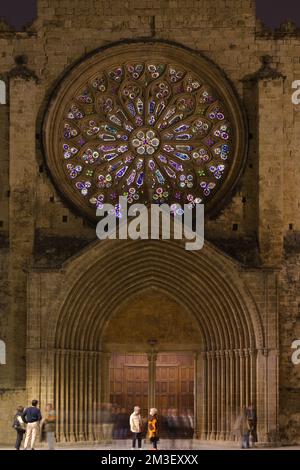 Lunga esposizione della parte anteriore del monastero di Sant Cugat di notte con la sua rosetta di vetro colorato, con persone di fronte ad esso con qualche movimento sfocato. Foto Stock