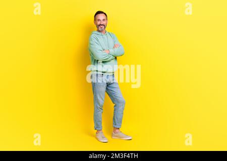 Foto a tutta lunghezza di buon uomo che guarda indossare abiti alla moda braccio incrociato stand vuoto spazio banner annuncio isolato su sfondo di colore giallo Foto Stock