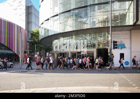 Turisti e visitatori che attraversano la strada fuori Debenhams e Costa Lord Street a Liverpool One Foto Stock