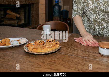 Donna panni tavolo con straccio. La mano della donna pulisce i piatti dopo aver mangiato. Foto di alta qualità Foto Stock