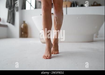 Vista in sezione bassa dei piedi femmina bagnati e schiumosi sul pavimento del bagno Foto Stock