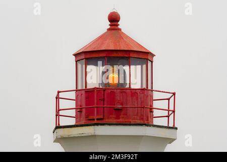 Cima di un faro in una giornata di nebbia. Il faro è vecchio e un po' arrugginito ma funzionante. Cielo coperto e nebbia sullo sfondo. Foto Stock