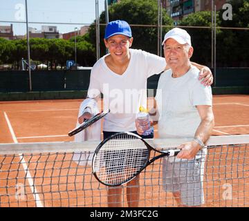 nonno e nipote in posa sul campo da tennis Foto Stock