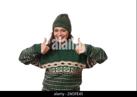 Allegra afroamericana bella donna in caldi abiti di lana, sorridendo un sorriso toothy e mostrando pollici fino alla macchina fotografica Foto Stock