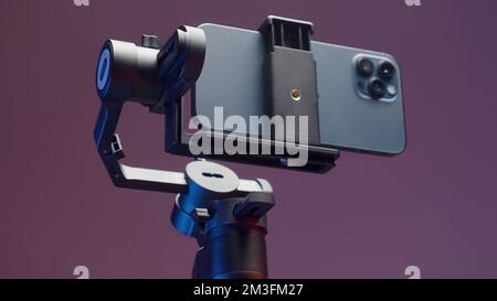 Stabilizzatore per smartphone con tre fotocamere isolate su una parete rosa. Azione. Nuova soluzione professionale per le riprese e un telefono Foto Stock