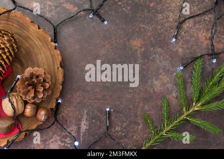 Spianatura natalizia contenente coni, noci e luci delle fate con spazio per la copia su sfondo scuro Foto Stock