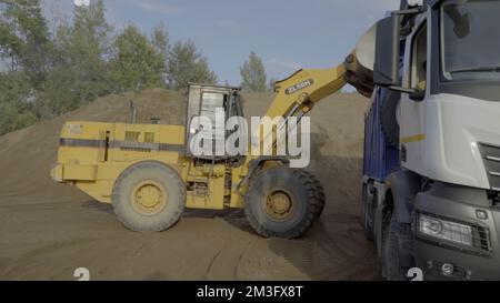 Berlino, Germania - 20 giugno 2022: Diverse macchine lavorano in una cava di pietra. Scenografia. Background industriale con trattori e autocarri che caricano pietre e s. Foto Stock