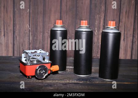 bruciatore turistico a gas e bombolette spray sul tavolo. Foto di alta qualità Foto Stock