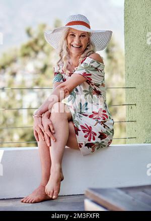 Sono molto soddisfatto con la mia vita ora. Ritratto completo di una bella donna anziana sorridente mentre si siede all'aperto in un giorno d'estate. Foto Stock