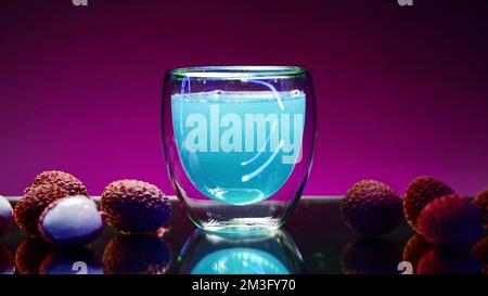 Cocktail blu su un banco bar con bacche di lychee. Clip di scorta. Concetto di vita notturna, discoteca bar e divertimento Foto Stock