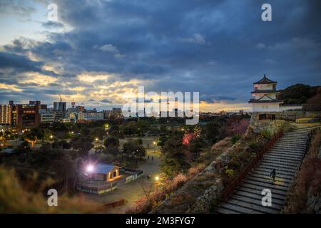 Il suggestivo tramonto si interrompe attraverso le nuvole sullo storico parco del castello giapponese Foto Stock