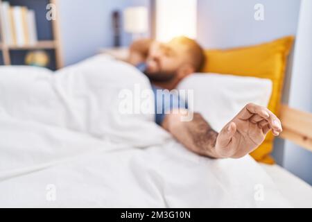 Giovane ispanico che si svegliò stendendo le braccia in camera da letto Foto Stock