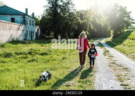 Donna anziana alla moda e la sua bambina godendo una passeggiata in campagna con il loro cane beagle - nonna e nipote felici insieme Foto Stock