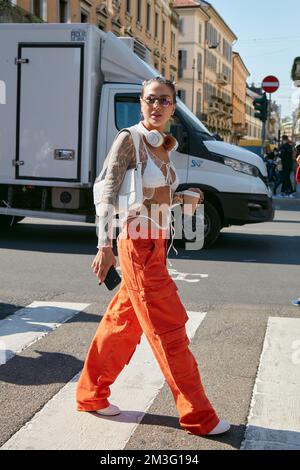 MILANO, ITALIA - 23 SETTEMBRE 2022: Donna con pantaloni cargo arancio e reggiseno bianco prima della sfilata Sportmax, Milano Fashion Week Street Style Foto Stock