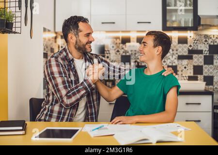 Padre sta aiutando suo figlio con l'apprendimento. Stanno facendo i compiti insieme. Foto Stock