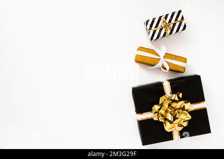 Composizione di Natale. Regali di Natale, carta da imballaggio nera e dorata su sfondo bianco Foto Stock