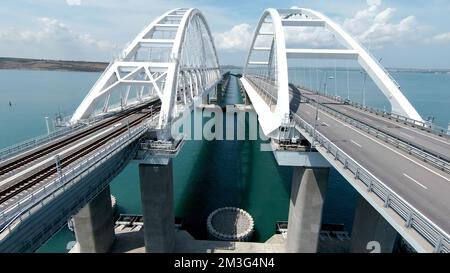 Un grande ponte con auto rare in movimento. Scatto. Vista aerea di un volo sopra il ponte con acqua turchese su uno sfondo cielo nuvoloso blu Foto Stock