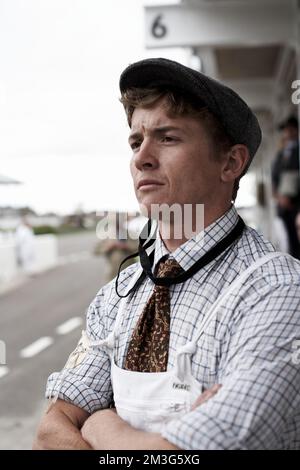 West Sussex, Inghilterra : meccanico che guarda la corsa nel paddock al Goodwood Revival . Foto Stock