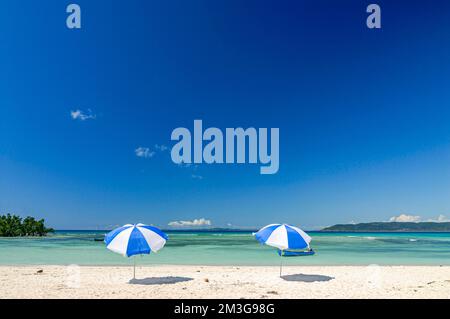 Ombrelloni su una bella spiaggia di sabbia bianca, isola di Nosy Iranja vicino a Nosy Be, Madagascar Foto Stock