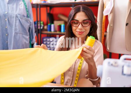 Giovane bella donna araba sartoriale reggendo la stoffa e il filo all'atelier Foto Stock