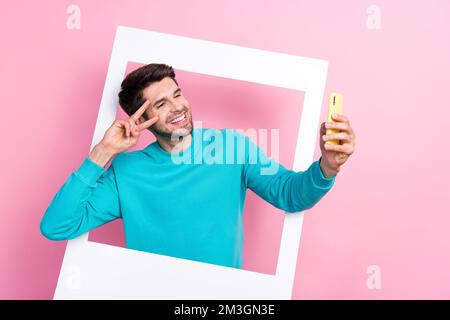 Ritratto fotografico di giovane ragazzo attraente polaroid foto cornice selfie Hold dispositivo indossare abiti blu alla moda isolato su sfondo di colore rosa Foto Stock