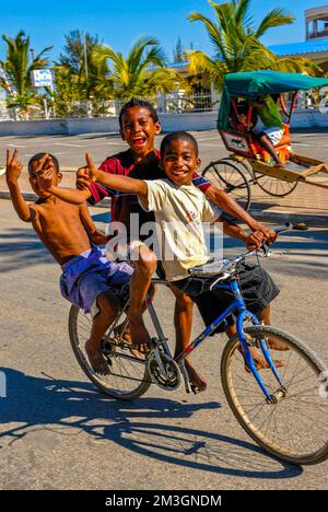 Happy boys in bicicletta attraverso le strade di Toliara, Madagascar Foto Stock