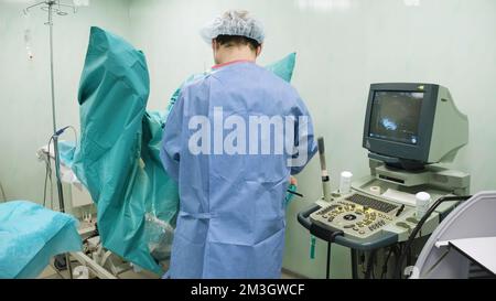 Il medico prepara gli strumenti e le tecnologie per il funzionamento. Creativo. Il medico si sta preparando all'intervento chirurgico in sala operatoria. Il chirurgo prepara strumenti e pl Foto Stock