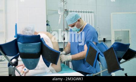 Il medico prepara il paziente per l'intervento chirurgico. Creativo. Il paziente si siede mentre il medico prepara il paziente per l'intervento chirurgico in sala operatoria. Preparazione e iniezione di Foto Stock