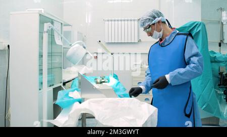 Il medico prepara gli strumenti e le tecnologie per il funzionamento. Creativo. Il medico si sta preparando all'intervento chirurgico in sala operatoria. Il chirurgo prepara strumenti e pl Foto Stock