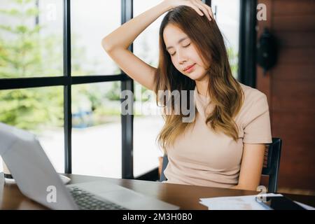 Donna d'affari freelance che soffre di dolore al collo causato da un uso prolungato del notebook Foto Stock