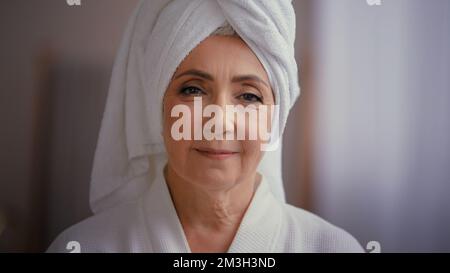 Caucasian vecchio anziano maturo attraente donna di mezza età 60s lady 50s modello femminile che indossa accappatoio e asciugamano bianco sulla testa con volto ruggito guardare Foto Stock