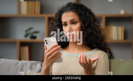 Ispanica triste donna dispiacuta ha problemi con l'app mobile online sul telefono cellulare infelice con il blocco account nei social network guardando il cellulare Foto Stock