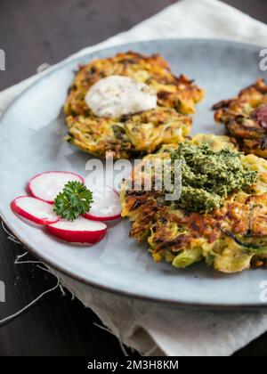 Frittelle di zucchine vegane fatte in casa con tre salse. Foto Stock