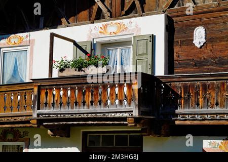 Una tradizionale casa alpina bavarese rustica con gerani sulla sporgenza del balcone e un bel balcone in legno intagliato nelle Alpi bavaresi a Garmisch Foto Stock