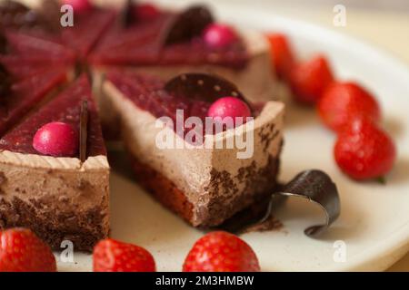 torta al cioccolato con fragole primo piano. affettare con gocce di cioccolato e souffle. Pasticceria Foto Stock