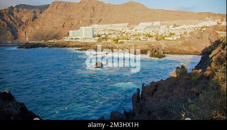 Costa vulcanica nella città di Puerto de Santiago, onde che colpiscono le rocce, piscina naturale nel sud di Tenerife, Isole Canarie, Spagna. Il mare è tempestoso. Foto Stock