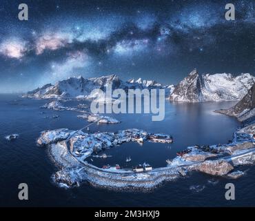 Veduta aerea dell'arco della Via Lattea, del mare, del villaggio e delle montagne innevate Foto Stock