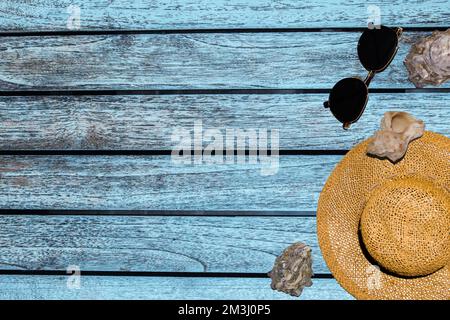 striscioni per la pubblicità occhiali da cappello conchiglie su uno sfondo di legno di colore blu Foto Stock