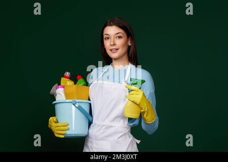 donna in grembiule detergente che tiene secchio di detergenti Foto Stock