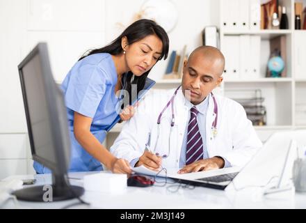 Dottore firma carte portato da donna assisant in ufficio medico Foto Stock