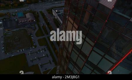 Vista aerea di un moderno grattacielo di uffici in vetro con riflessi della città nelle finestre. Riprese in stock. Volare sopra la città moderna su un Foto Stock