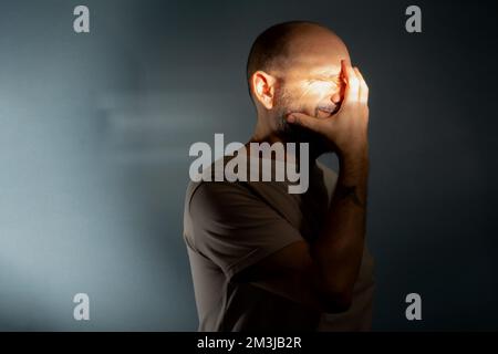Depresso uomo di mezza età con mano su faccia isolato su sfondo grigio, con problemi finanziari o soffrendo di solitudine. Foto Stock