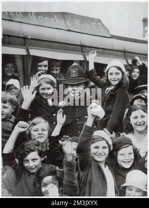 Un poliziotto circondato da bambini provenienti dall'East End di Londra,  prima di partire per una gita di un giorno in campagna, a West India Docks,  Londra, 1936. La gita giornaliera era stata