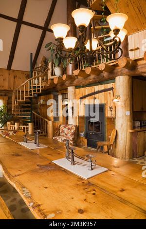 Antico lampadario sopra il tavolo da pranzo in tronchi divisi nella sala da pranzo all'interno di una rustica capanna in tronchi. Foto Stock